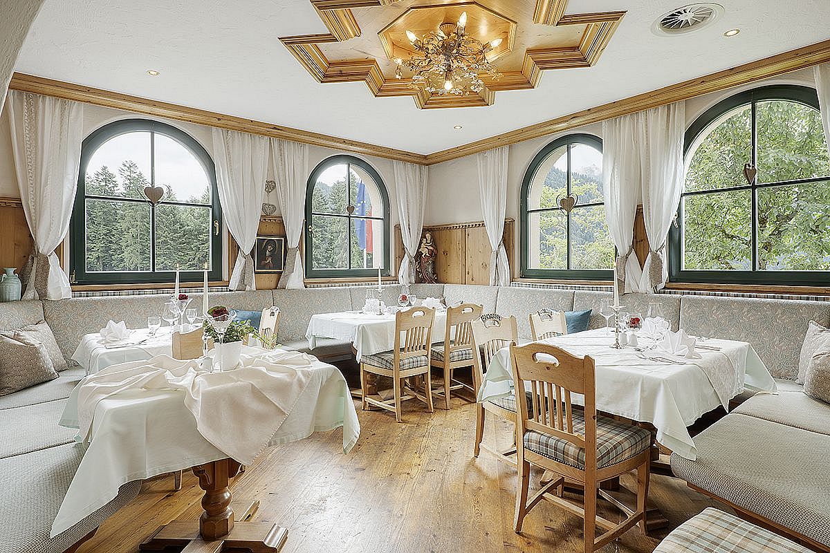 Helles Stüberl im Hotel AlpenSchlössl mit gedeckten Tischen und Panoramafenstern