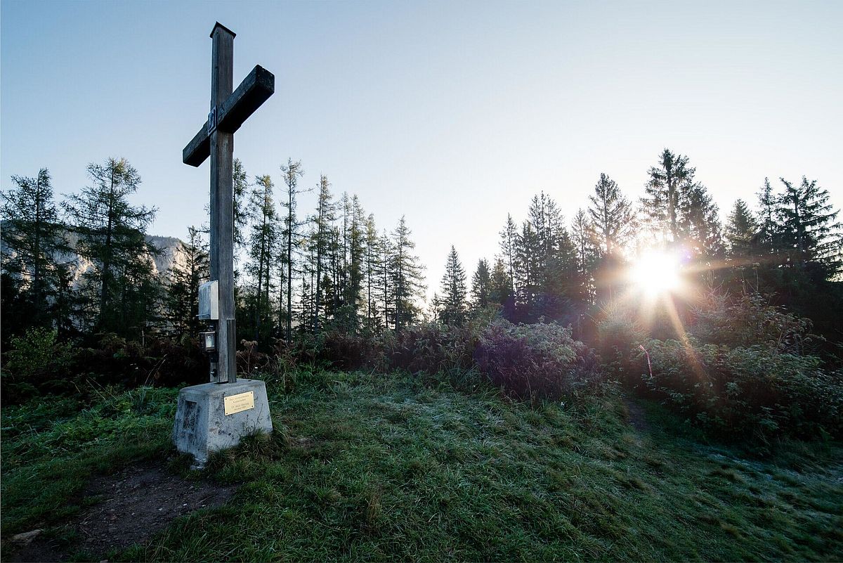 Gipfelkreuz in Söll am Wilden Kaiser bei Sonnenlicht im Wald